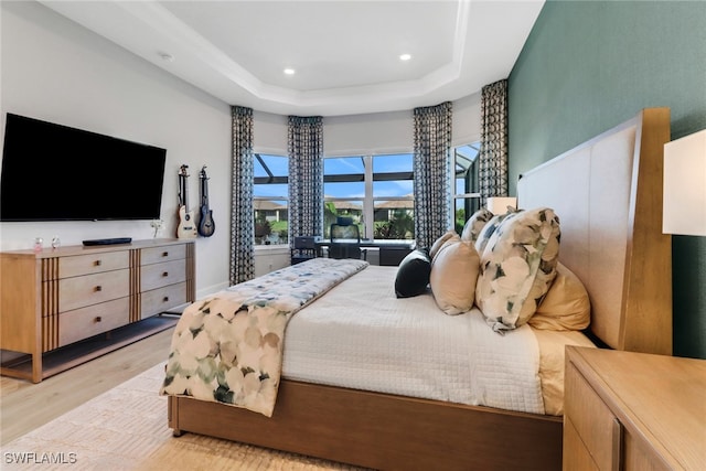 bedroom with a tray ceiling and light hardwood / wood-style flooring