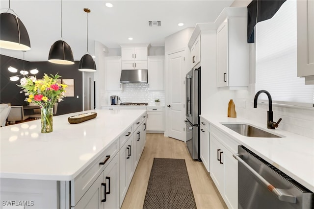 kitchen featuring appliances with stainless steel finishes, sink, light hardwood / wood-style flooring, a center island, and white cabinetry