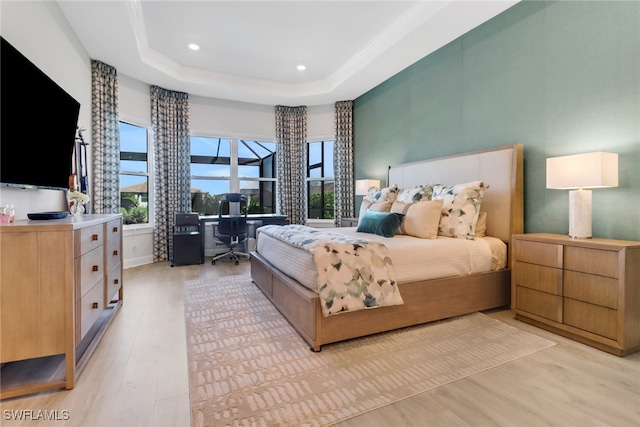 bedroom with a raised ceiling and light wood-type flooring