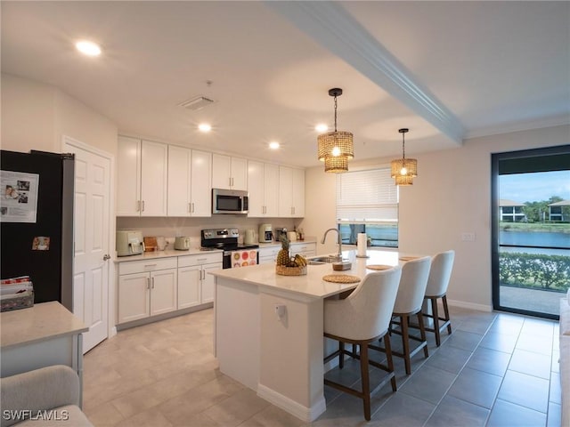 kitchen with white cabinetry, appliances with stainless steel finishes, a center island with sink, and decorative light fixtures