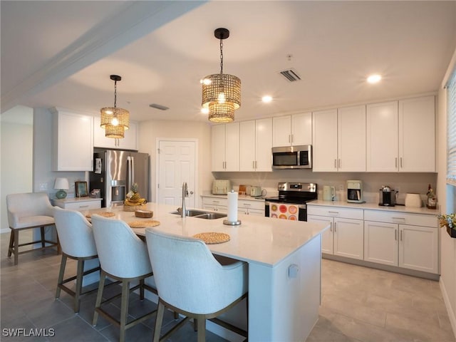 kitchen with decorative light fixtures, white cabinetry, sink, a kitchen island with sink, and stainless steel appliances