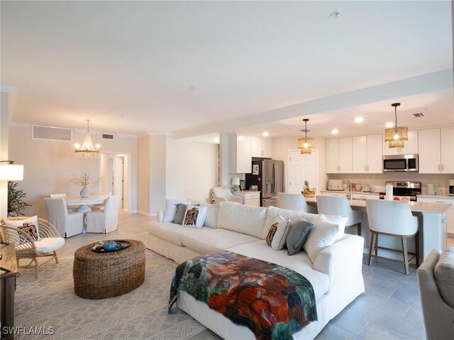 living room featuring an inviting chandelier, light tile patterned floors, and ornamental molding