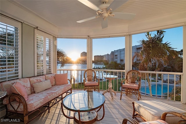 sunroom / solarium with ceiling fan and a water view