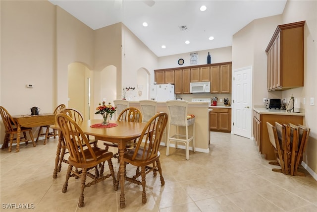 dining space with high vaulted ceiling and light tile patterned floors