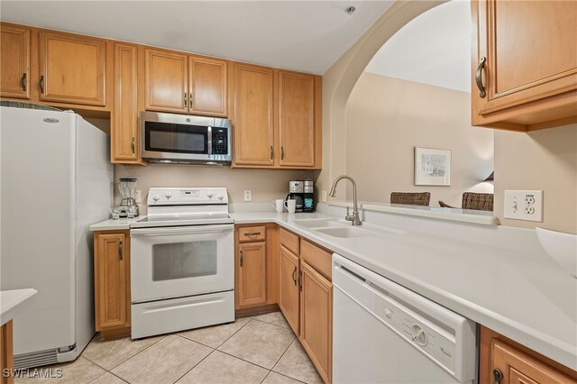 kitchen featuring white appliances, kitchen peninsula, sink, and light tile patterned floors