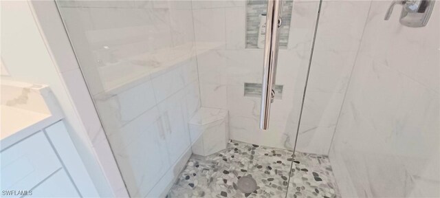 bathroom with tiled shower and vanity