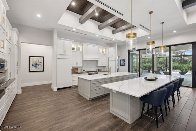 kitchen featuring a large island, dark hardwood / wood-style flooring, beamed ceiling, pendant lighting, and white cabinets