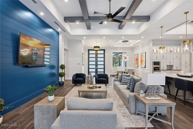 living room with dark hardwood / wood-style flooring, beamed ceiling, and ceiling fan with notable chandelier