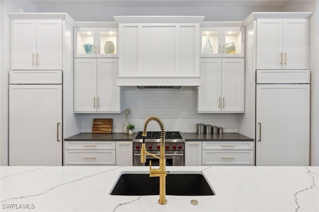 kitchen with white cabinets, high end appliances, dark stone countertops, and tasteful backsplash