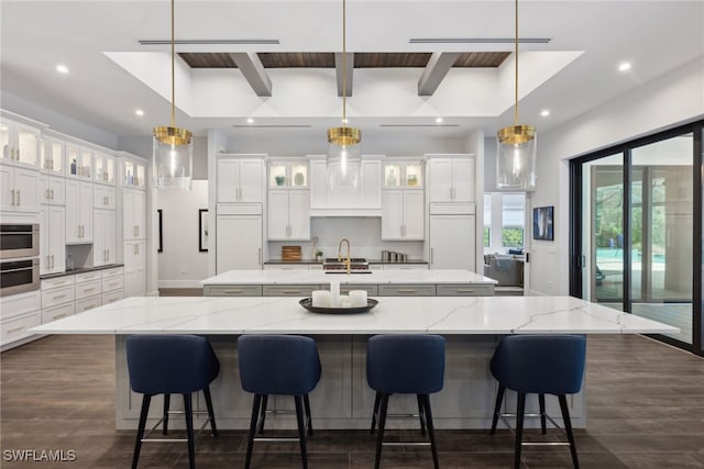 kitchen with dark hardwood / wood-style flooring, white cabinetry, hanging light fixtures, and a large island with sink