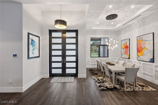 dining area featuring french doors, a raised ceiling, and dark wood-type flooring