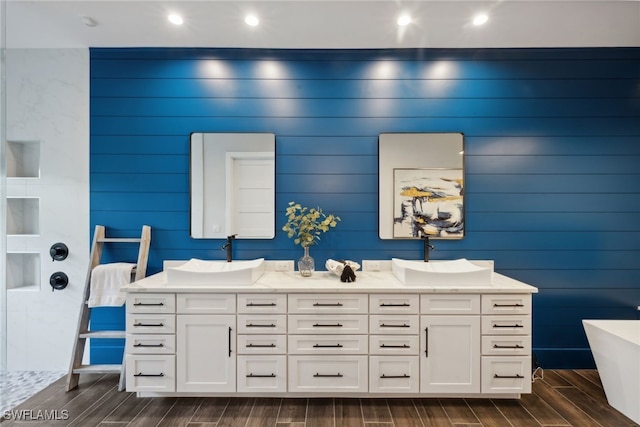 bathroom featuring a bath, wood-type flooring, vanity, and wooden walls