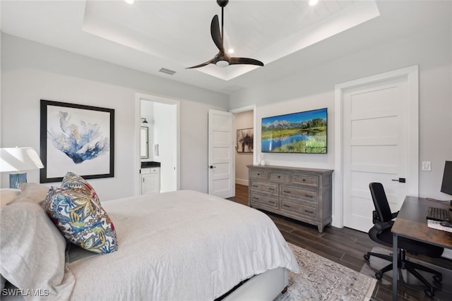 bedroom featuring ceiling fan, dark hardwood / wood-style floors, a raised ceiling, and ensuite bath