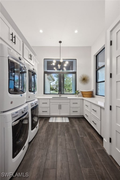 washroom with cabinets, stacked washer and dryer, dark hardwood / wood-style floors, and plenty of natural light