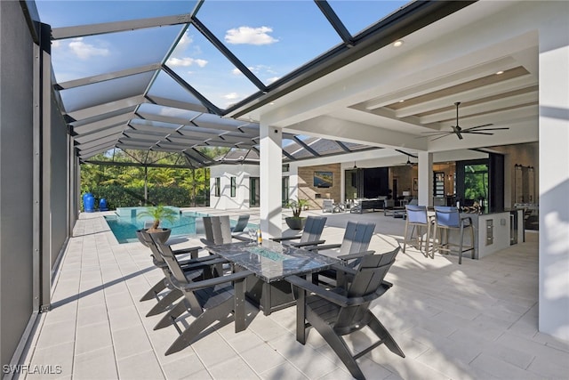 view of patio / terrace featuring glass enclosure, ceiling fan, and an outdoor bar