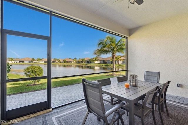 sunroom / solarium featuring a residential view, a ceiling fan, and a water view