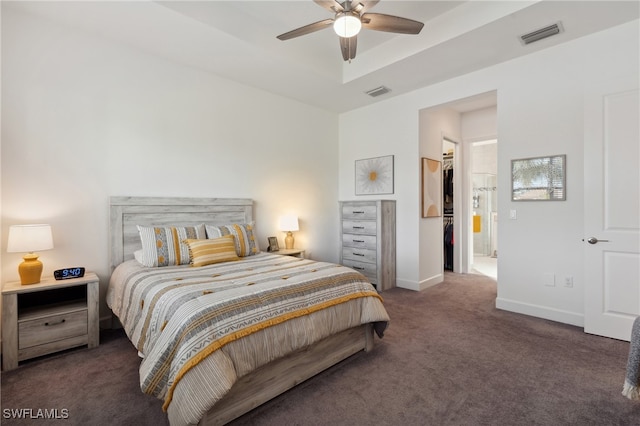 bedroom with ceiling fan, a closet, dark carpet, and a spacious closet