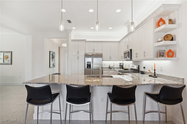 kitchen featuring kitchen peninsula, stainless steel appliances, sink, decorative light fixtures, and white cabinets