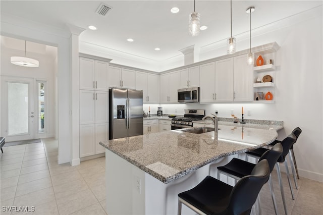 kitchen featuring a breakfast bar, hanging light fixtures, ornamental molding, light stone counters, and stainless steel appliances