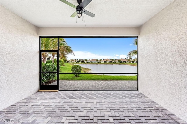 unfurnished sunroom featuring a ceiling fan and a water view