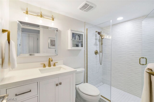 bathroom featuring vanity, toilet, and a shower with shower door