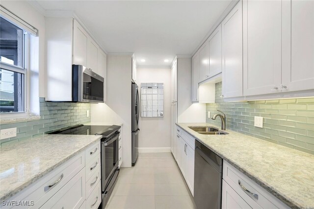 kitchen with light stone counters, sink, stainless steel appliances, and white cabinets