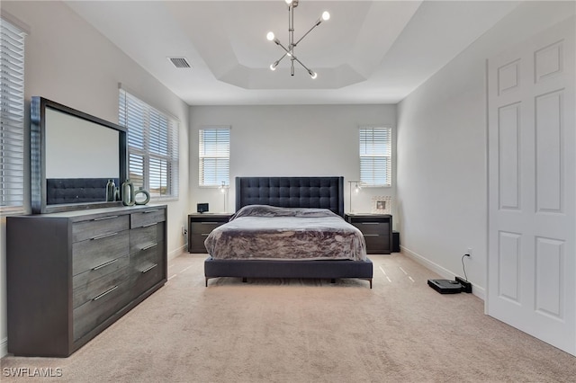 bedroom with light colored carpet, an inviting chandelier, and a tray ceiling