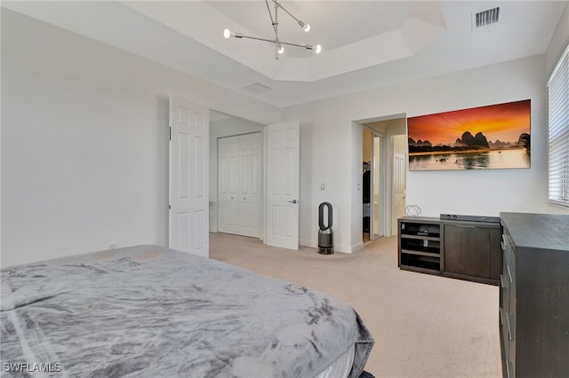 carpeted bedroom with a chandelier, a raised ceiling, and a closet