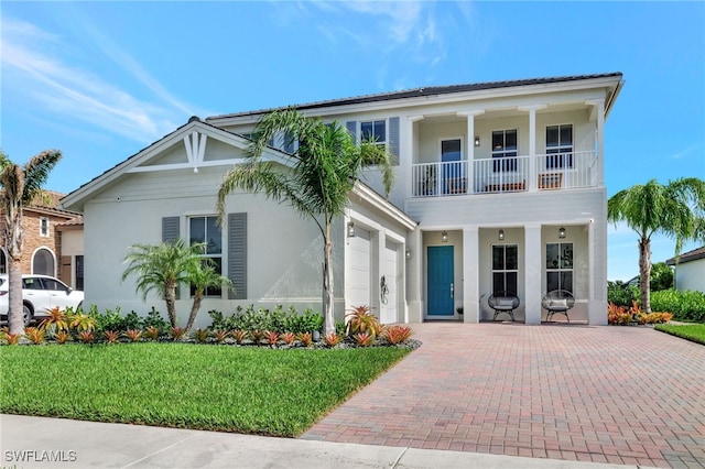 view of front facade with a balcony, a garage, and a front lawn