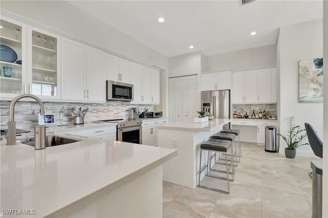 kitchen with white cabinetry, a center island, sink, stainless steel appliances, and a breakfast bar area