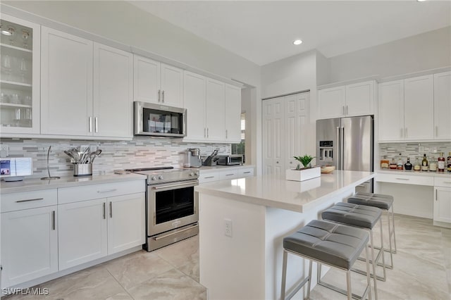 kitchen featuring a breakfast bar, a center island, tasteful backsplash, white cabinetry, and stainless steel appliances