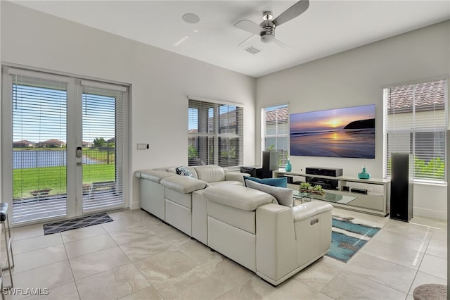 living room with light tile patterned flooring, a water view, plenty of natural light, and ceiling fan