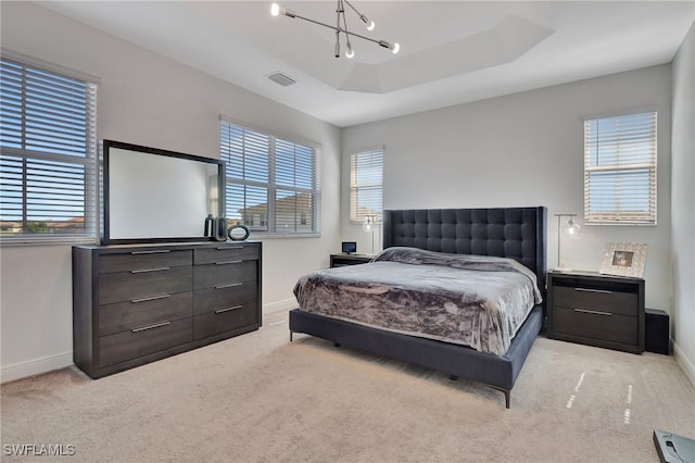 bedroom featuring light carpet, an inviting chandelier, and a raised ceiling