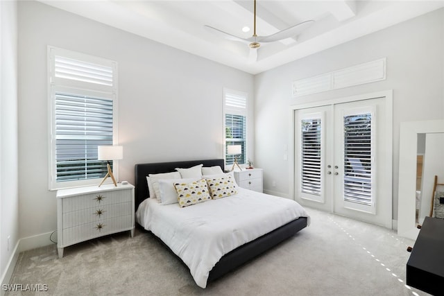 carpeted bedroom featuring a tray ceiling, access to outside, and french doors