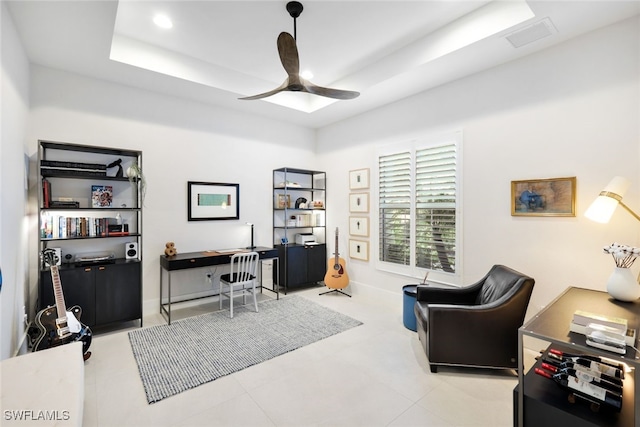 home office featuring ceiling fan and a tray ceiling