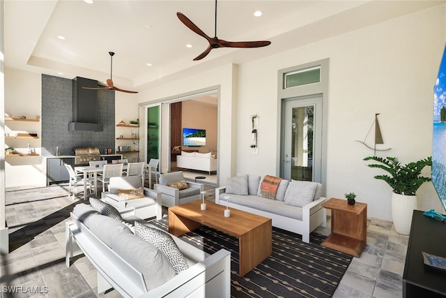 living room featuring a tray ceiling, a fireplace, and ceiling fan