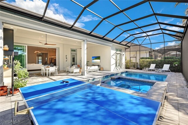 view of swimming pool with ceiling fan, glass enclosure, a patio area, an outdoor hangout area, and an in ground hot tub