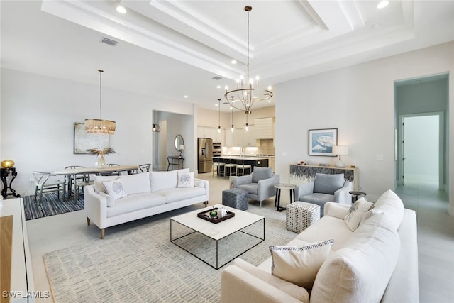 living room with a tray ceiling, a high ceiling, and a notable chandelier