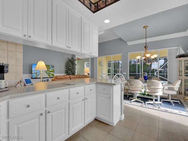 kitchen featuring an inviting chandelier, kitchen peninsula, light tile patterned floors, decorative light fixtures, and white cabinetry