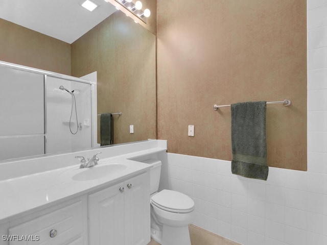 bathroom featuring vanity, toilet, a shower, and tile walls