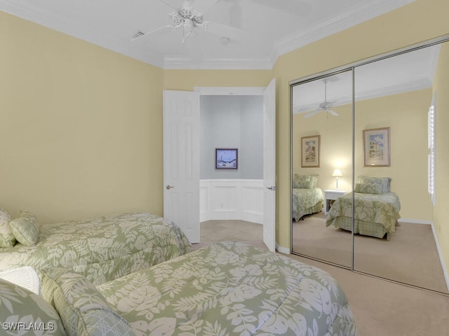 bedroom with ceiling fan, a closet, light colored carpet, and ornamental molding