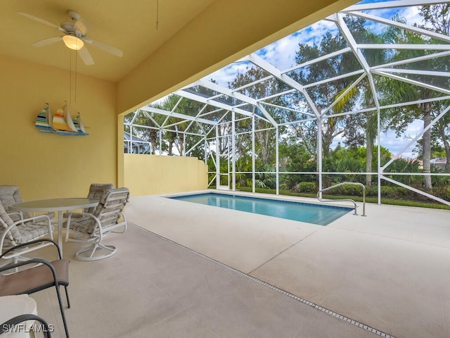 view of swimming pool with ceiling fan, a patio, and glass enclosure