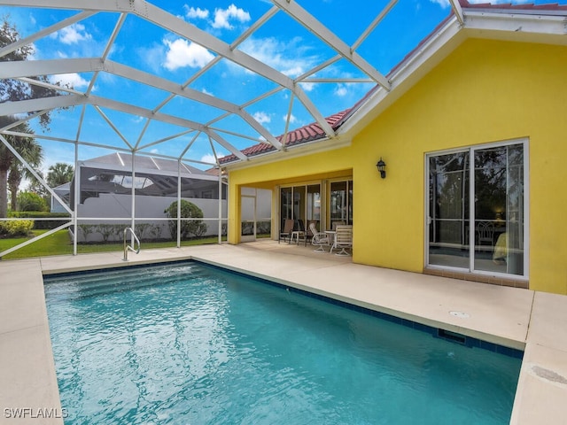 view of swimming pool with glass enclosure and a patio