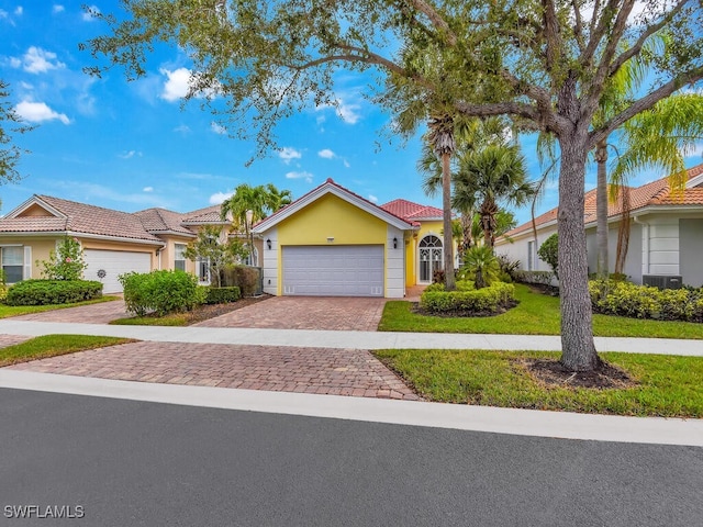 view of front of house with cooling unit, a garage, and a front yard