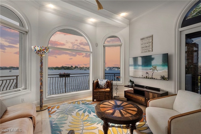 living area with beam ceiling, hardwood / wood-style floors, and ornamental molding