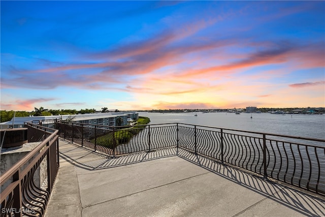 patio terrace at dusk with a water view and a balcony