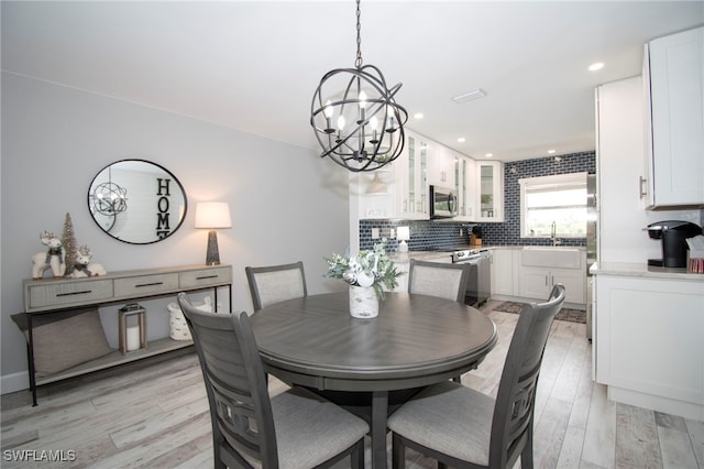 dining room with light hardwood / wood-style flooring, a notable chandelier, and sink