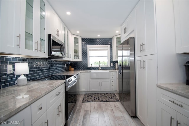 kitchen featuring sink, light hardwood / wood-style floors, light stone counters, white cabinetry, and stainless steel appliances