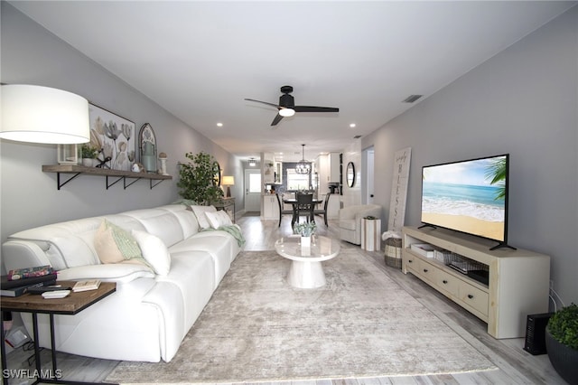 living room featuring light hardwood / wood-style floors and ceiling fan with notable chandelier