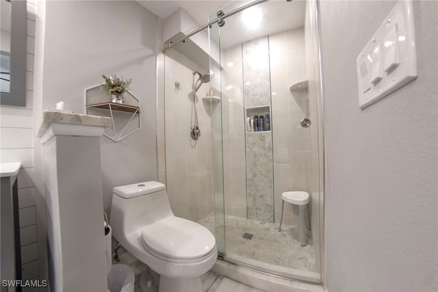 bathroom featuring toilet and a shower with door